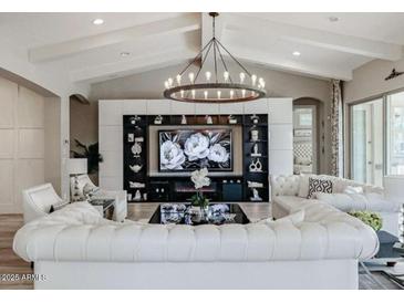 Elegant living room featuring white sofas, a large TV, and a stunning chandelier at 2351 E Cherrywood Pl, Chandler, AZ 85249