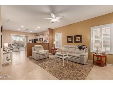 Open living room with beige walls, light leather sofas, and tile floors at 26222 W Behrend Dr, Buckeye, AZ 85396