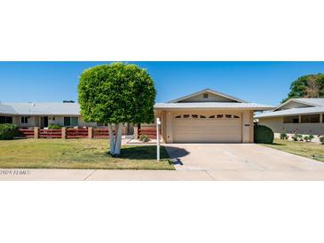 Tan house with attached garage and manicured lawn at 10742 W Cheryl Dr, Sun City, AZ 85351