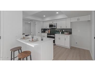 Modern white kitchen with island, new appliances, and dark green tile backsplash at 13614 N Hawthorn Dr, Sun City, AZ 85351