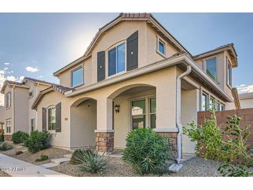 Two-story house with light-colored siding, shutters, and landscaping at 14238 W Bronco Trl, Surprise, AZ 85387