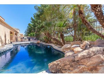 Inviting swimming pool surrounded by rocks and lush landscaping at 3731 E Fruitvale Ave, Gilbert, AZ 85297