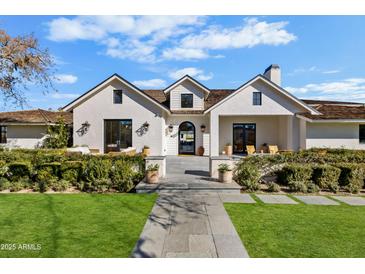 Stunning white farmhouse exterior with a welcoming front porch and lush landscaping at 5314 E Calle Del Norte --, Phoenix, AZ 85018