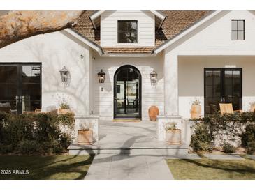 Inviting front entrance features a black arched doorway, stylish lanterns, and manicured landscaping at 5314 E Calle Del Norte --, Phoenix, AZ 85018