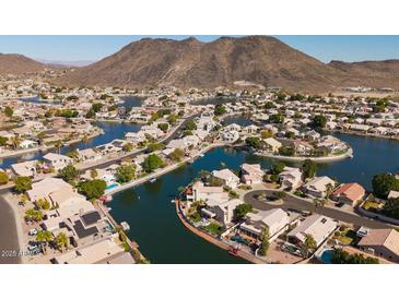 Aerial view of lakefront community with numerous houses and mountain backdrop at 5415 W Pontiac Dr, Glendale, AZ 85308