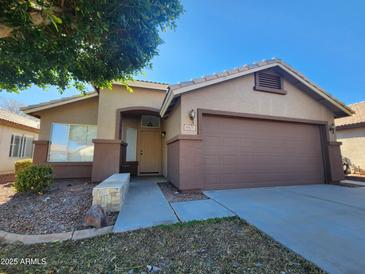 Single story home with tan exterior, two car garage, and landscaped front yard at 8605 W Paradise Dr, Peoria, AZ 85345