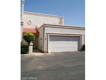 Front view of a light-colored townhouse with a red tile roof and attached garage at 8719 N Fountain Dr, Peoria, AZ 85345