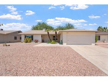 Charming single-story home featuring a two-car garage, mature palm trees, and low maintenance desert landscaping at 11802 S Half Moon Dr, Phoenix, AZ 85044