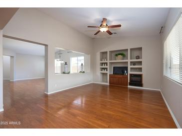 Bright living room with hardwood floors, built-in shelving, and a view to the dining area at 2115 W Harwell Rd, Phoenix, AZ 85041