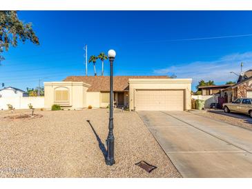 Tan house with a two-car garage and gravel driveway at 5448 W Shaw Butte Dr, Glendale, AZ 85304