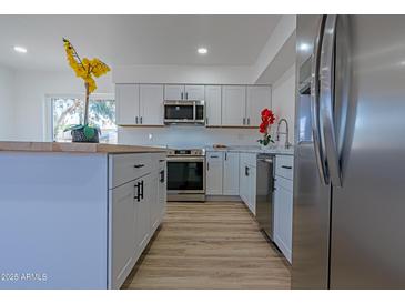 Modern kitchen featuring white cabinets, stainless steel appliances, and a large island at 5725 W Osborn Rd, Phoenix, AZ 85031