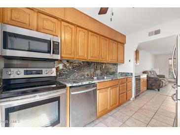 Modern kitchen with granite counters, stainless steel appliances, and wood cabinets at 8241 N Central Ave # 11, Phoenix, AZ 85020