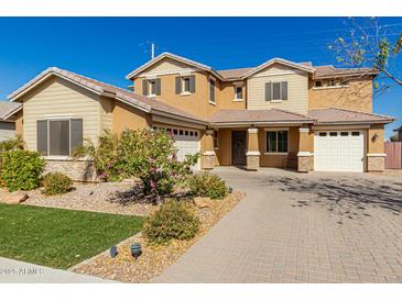 Beautiful two-story home featuring a three car garage, neutral desert color palette and manicured front yard at 20562 E Raven Dr, Queen Creek, AZ 85142