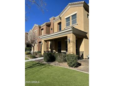 Tan stucco townhome with front porch, landscaping, and artificial turf at 312 W Herro Ln, Phoenix, AZ 85013