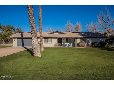 Charming single-story home with a well-manicured lawn, lush landscaping, and a cozy porch with blue chairs at 616 E Country S Plz, Gilbert, AZ 85234