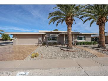 Updated mid-century ranch home with a large front yard and mature palm trees at 9215 W Raintree Dr, Sun City, AZ 85351