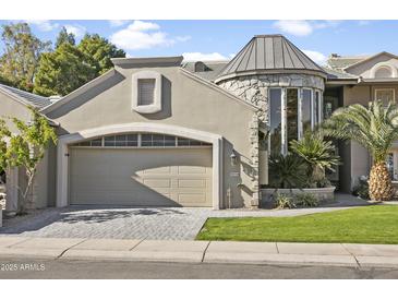 Tan two-story house with a stone turret, a large garage, and a manicured lawn at 10796 N 78Th St, Scottsdale, AZ 85260
