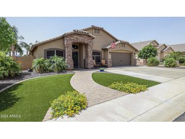 Beautiful ranch home with a stone facade, landscaped yard, and a paved pathway at 10405 W Patrick Ln, Peoria, AZ 85383