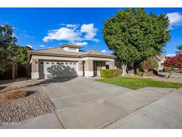 Single-story home with stone accents, a two-car garage, and a landscaped lawn at 12548 W Monterosa St, Litchfield Park, AZ 85340