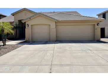 Tan home featuring a two-car garage, desert landscaping, and a tile roof, perfect for low-maintenance living at 861 E Toledo St, Gilbert, AZ 85295