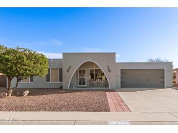 Brick ranch house with arched entry, attached garage, and landscaped yard at 9226 W Glen Oaks N Cir, Sun City, AZ 85351