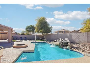 Inviting backyard oasis featuring a sparkling pool and waterfall feature at 22194 N Kingston Dr, Maricopa, AZ 85138