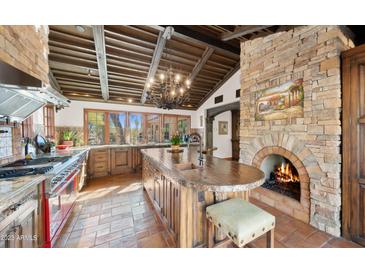 Spacious kitchen features a stone fireplace, custom cabinetry, and high-end appliances at 35035 N Whileaway Rd, Carefree, AZ 85377