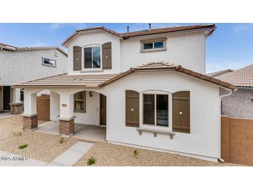 Charming two-story home showcasing neutral exterior paint, brown shutters, and a well-manicured front yard at 14670 W Sand Hills Rd, Surprise, AZ 85387