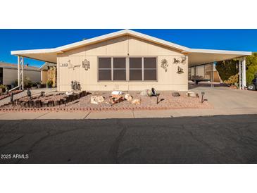 Tan mobile home with covered carport, landscaped yard, and decorative accents at 6209 E Mckellips Rd # 446, Mesa, AZ 85215