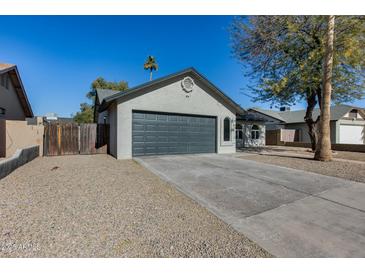 Ranch style home with gray garage door and landscaped yard at 6934 W Mclellan Rd, Glendale, AZ 85303