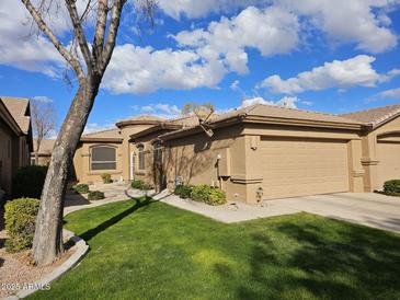 Tan stucco house with a two-car garage and landscaped front yard at 9610 E Rocky Lake Dr, Sun Lakes, AZ 85248
