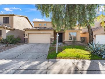 Two-story house with a beige exterior, landscaped yard, and a two-car garage at 9931 W Odeum Ln, Tolleson, AZ 85353