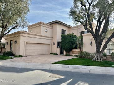 Beige two-story home featuring an attached garage, well-kept lawn, and mature shade trees at 10113 E Topaz Dr, Scottsdale, AZ 85258