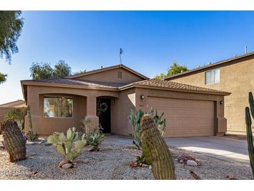 Front view of a tan house with cacti and a two-car garage at 1133 E Dust Devil Dr, San Tan Valley, AZ 85143