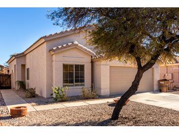 House exterior showcasing a tan stucco facade, two-car garage, and drought-tolerant landscaping at 13859 N 91St Ln, Peoria, AZ 85381