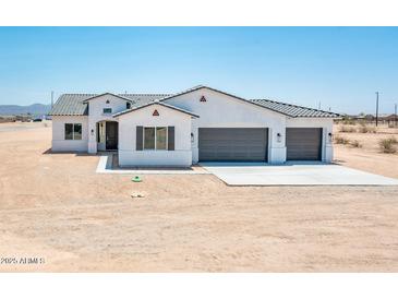 Charming single-story home with a three-car garage, desert landscaping, and a neutral color palette at 25505 W Brookhart Way, Wittmann, AZ 85361