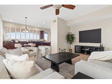 Bright living room with neutral color palette, modern furniture, ceiling fan, and view into kitchen area at 2742 N Augustine --, Mesa, AZ 85207