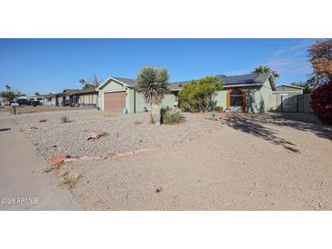 Ranch home with a spacious front yard, mature landscaping, and a two-car garage at 4938 W Michelle Dr, Glendale, AZ 85308