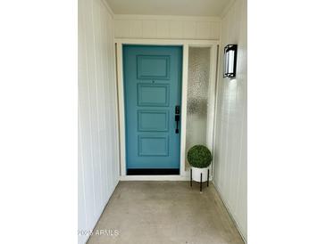 Inviting entryway with a teal door and modern light fixture at 10301 W Cheryl Dr, Sun City, AZ 85351