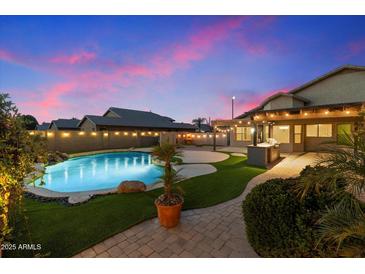 Inviting backyard oasis with sparkling pool, lush landscaping, and outdoor kitchen at 1157 E Liberty Ln, Gilbert, AZ 85296