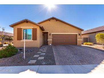 One-story house with tan exterior, brown garage door, and landscaped front yard at 17215 W Molly Ln, Surprise, AZ 85387