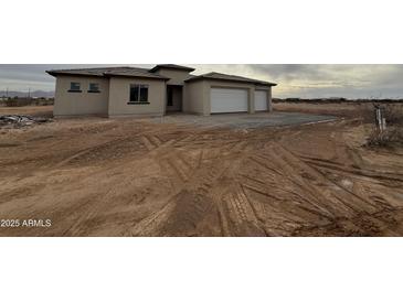 A single-story stucco home with a two car garage and desert landscaping at 25519 W Brookhart Way, Wittmann, AZ 85361