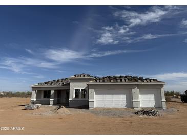 New construction home with a two-car garage under a blue sky ready for new roof tiles in a desert landscape at 29577 N 220Th Ave, Wittmann, AZ 85361