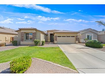 Tan single-story home with a well-manicured lawn, stone accents, and a two-car garage at 3383 E Santa Fe Ln, Gilbert, AZ 85297
