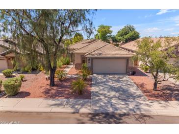 Single-story home with a tile roof, landscaped yard, and a two-car garage at 10387 W Runion Dr, Peoria, AZ 85382