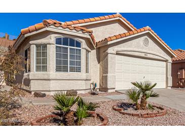 Tan stucco house with tile roof, two-car garage, and desert landscaping at 2018 E Glenhaven Dr, Phoenix, AZ 85048