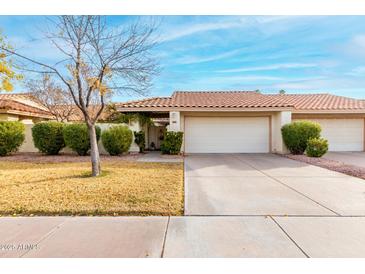 Tan stucco house with tile roof, two-car garage, and well-manicured lawn at 7373 S Bonarden Ln, Tempe, AZ 85283