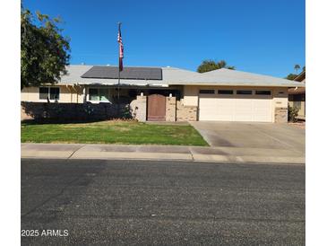 Single story home with solar panels, landscaped lawn, and a two-car garage at 10544 W Campana Dr, Sun City, AZ 85351