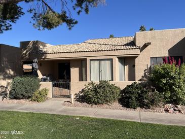 Spanish style home with tiled roof, gated entrance, and mature landscaping at 14300 W Bell Rd # 207, Surprise, AZ 85374