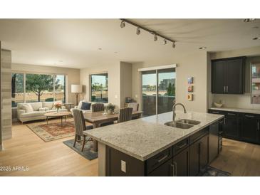 Open kitchen with granite island, stainless steel appliances, and dark cabinetry at 4805 N Woodmere Fairway Ln # 1012, Scottsdale, AZ 85251